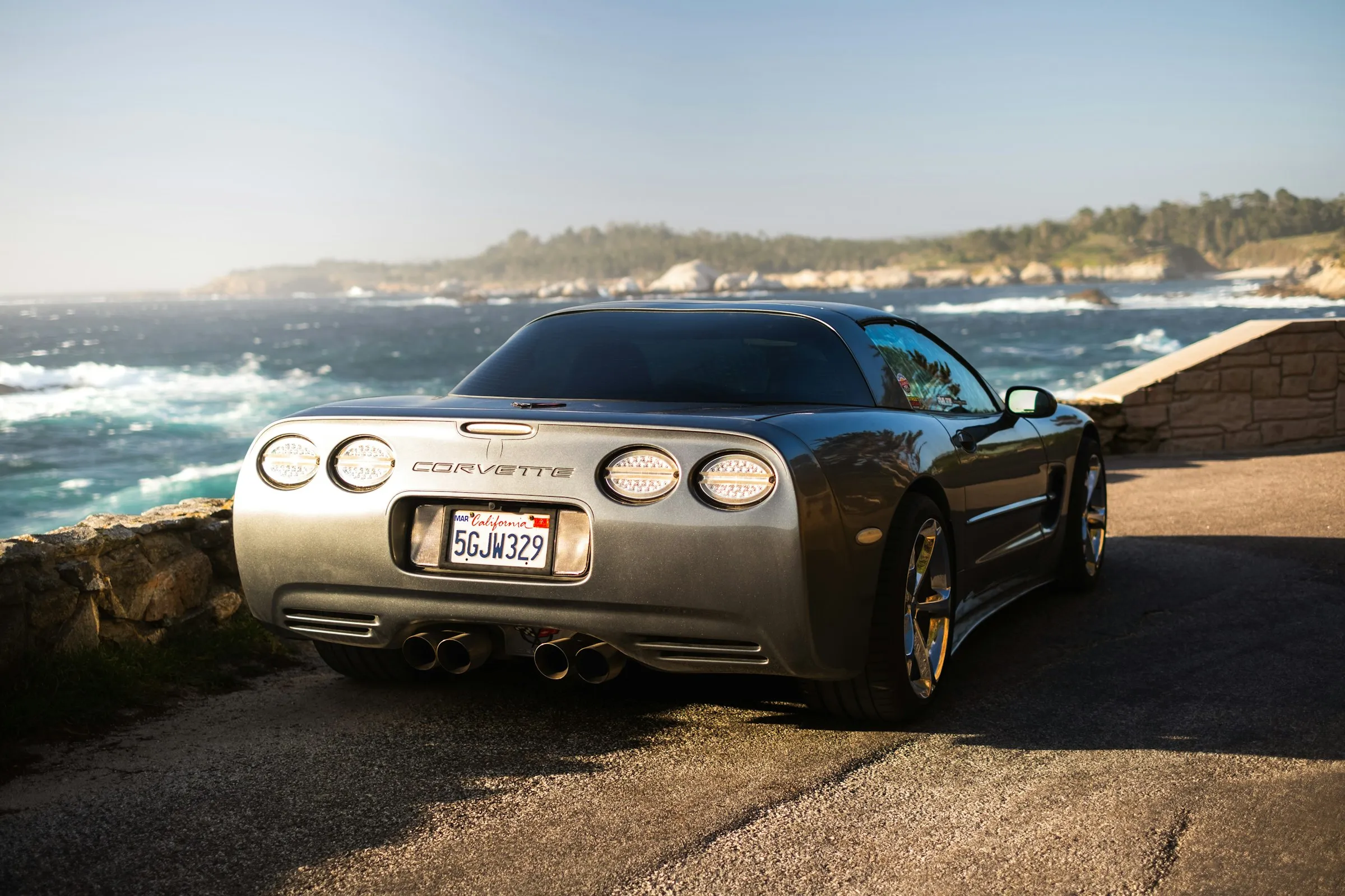 Rear of a car with a California license plate on a coastal road